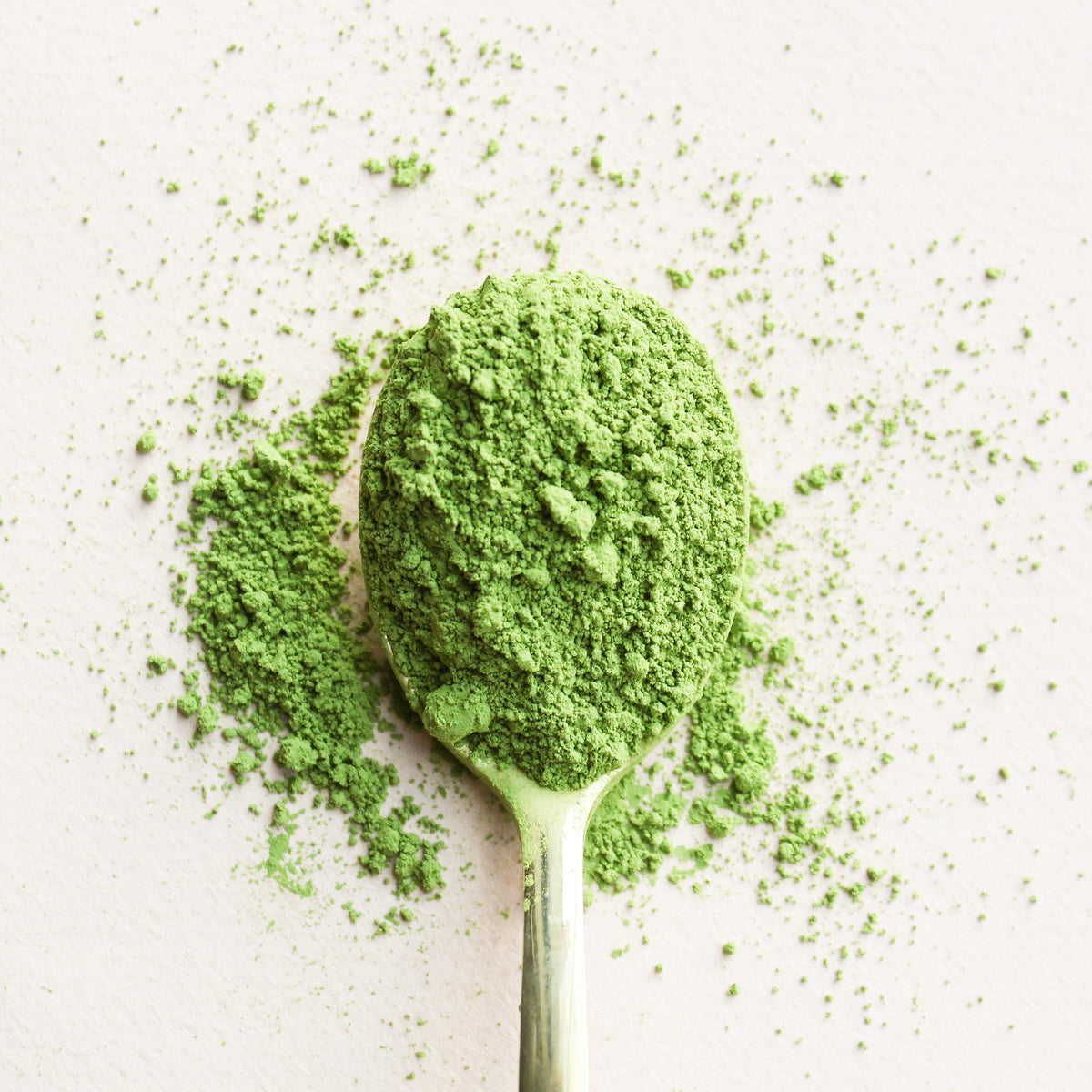 Spoonful of green powder on a light background