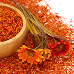 Dried saffron in a wooden bowl with saffron flowers on a white background