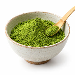 Matcha green tea powder in a ceramic bowl with bamboo scoop